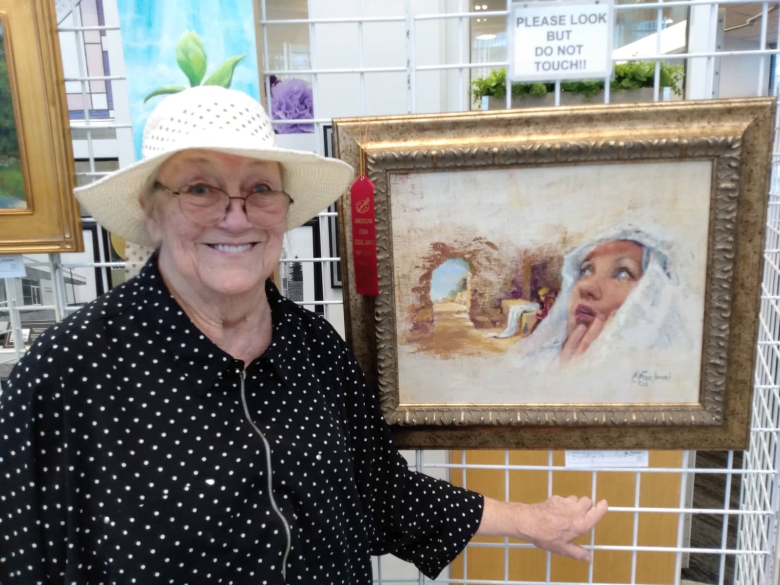 Linda Farrar smiling next to her award-winning oil painting at an art show
