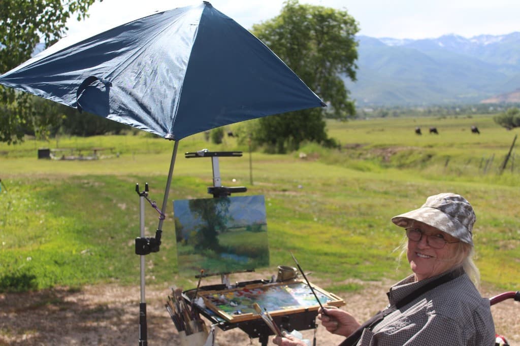 Linda Farrar painting plein air in a green meadow