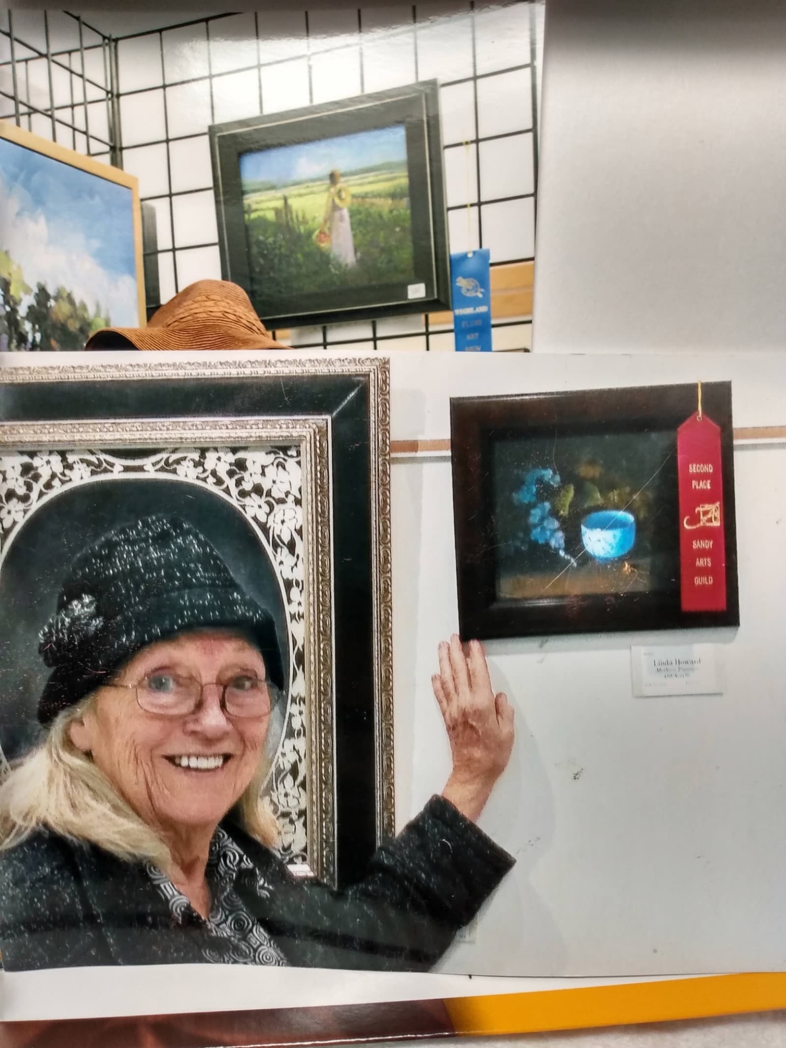 Linda Farrar standing with her award-winning paintings